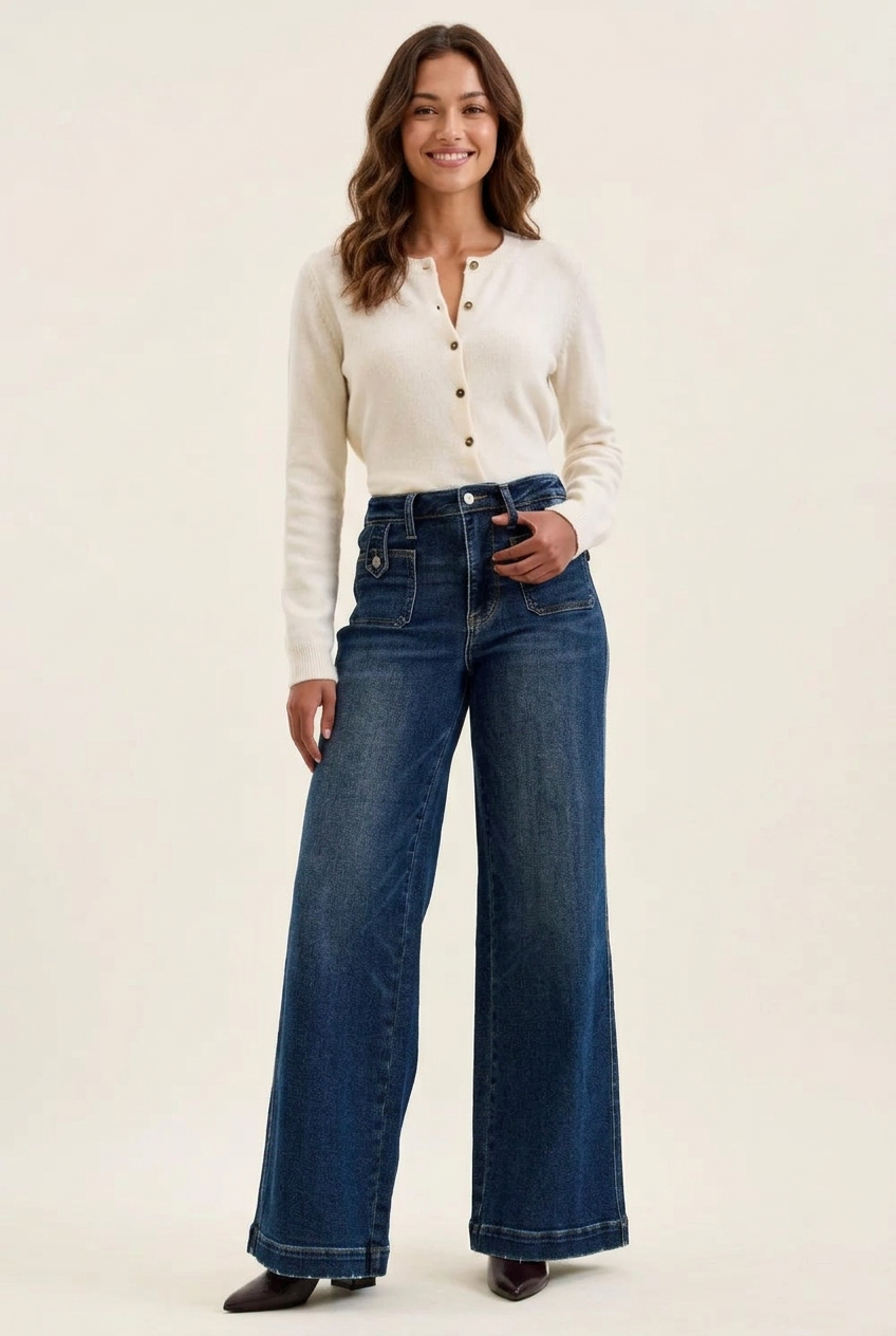 Smiling young adult model wearing Cristina dark wide-leg jeans and a cream buttoned cardigan.