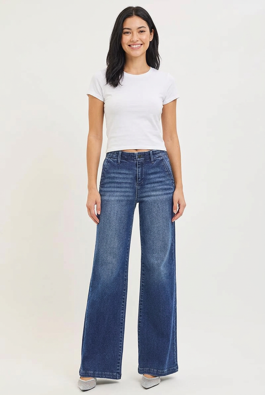 Smiling young adult model wearing Hazel dark wide-leg jeans with a white tee and silver shoes.